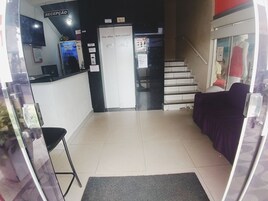 Uma área de recepção com balcão, escada e um manequim em uma vitrine.