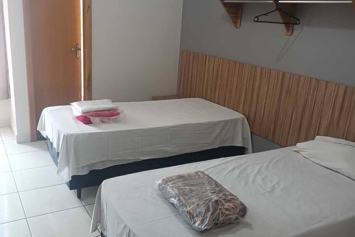 Une chambre d’hôtel avec deux lits, une tête de lit en bois, un climatiseur fixé au mur et une porte.