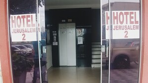 A entrada do Hotel Jerusalem 2, com uma placa visível, piso de azulejos e uma porta que dá acesso ao interior.