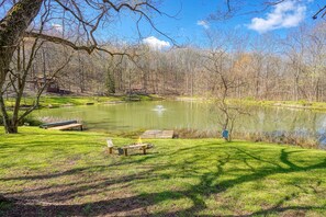 A serene lakeside park with a wooden dock, picnic table, and benches.