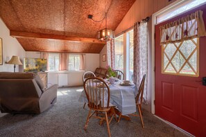 Un rincón comedor acogedor con una mesa de madera, sillas y una puerta roja.