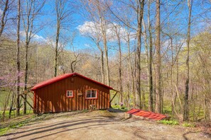 A wooden cabin with a red roof surrounded by a forest. - Wyandot Woods - Squirrels Nest (Laurelville)