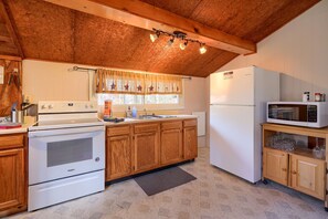 A kitchen with wooden cabinets, a stove, a microwave, and a refrigerator. - Wyandot Woods - Squirrels Nest (Laurelville)