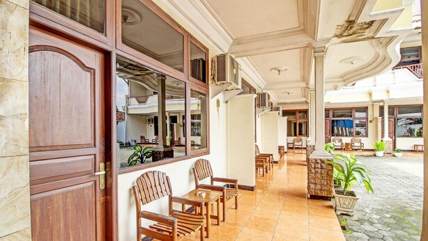 A hotel lobby with a tiled floor, wooden furniture, and potted plants. - Collection O 92242 Hotel Tanjung Emas (Purwokerto)