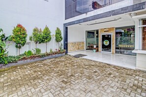 A courtyard with a paved floor, a small seating area, and a storefront with a sign. - Collection O 92242 Hotel Tanjung Emas (Purwokerto)