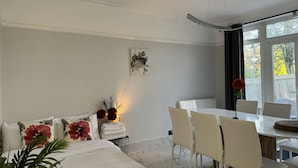 Een moderne slaapkamer met een bed, nachtkastje en een zithoek met stoelen en een tafel.