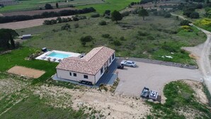 Una casa con piscina, un coche y una camioneta estacionados al frente.