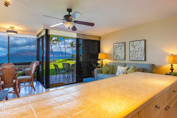 A modern room with a large bed, a ceiling fan, and a view of a tropical landscape.
