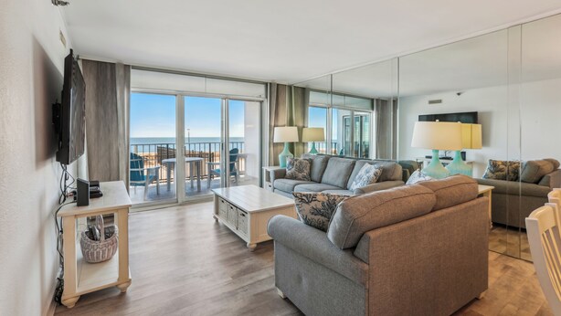 A modern living room with a sofa, two side tables, a coffee table, and a TV mounted on the wall.