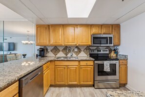 Una cocina moderna con armarios de madera, un microondas de acero inoxidable, un horno y encimeras de granito.