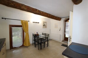 A dining area with a table and chairs, a window with curtains, and a door leading outside.