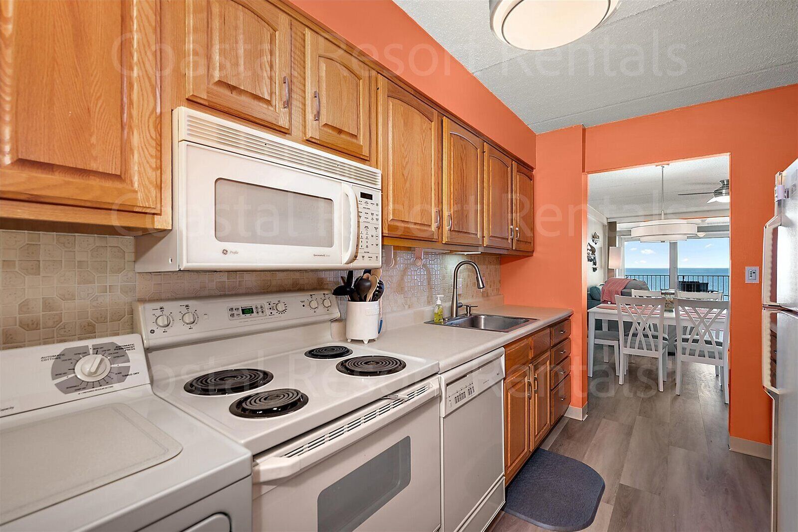 A kitchen with wooden cabinets, a white microwave, a stove, and a sink.