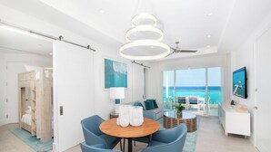 Ein modernes Hotelzimmer mit einem großen Balkon, einem runden Holztisch und blauen Stühlen.