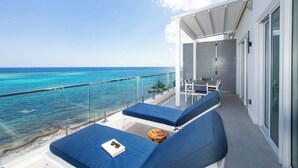 Ein Balkon mit blauen Sitzkissen, einem kleinen Tisch und Blick aufs Meer.