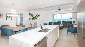 A modern kitchen with a large island, built-in appliances, and a view of the ocean. - Rum Point Resort 304 by Grand Cayman Villas (Seven Mile Beach)