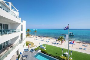 A hotel with a pool, lounge chairs, and a view of the beach and ocean.