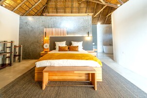 Quarto moderno com cama grande, banco de madeira e design de teto original.