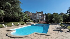 A swimming pool with lounge chairs and a stone building in the background. - Palais Toscan - Domaine d'exception (Sainte Foy)