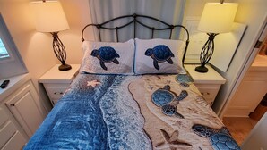 A bed with a blue and beige quilt featuring sea turtles and starfish. There are two bedside lamps on white nightstands. - Lakeside Cottage. Serene, Tranquil home. 2.mi.(4)mins from the Beach. Sleeps 3.  (Naples)