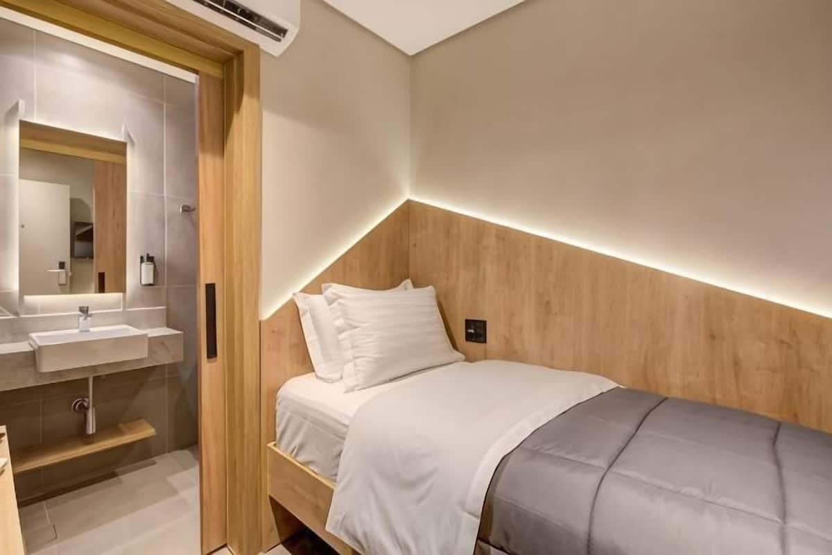 A bedroom with a wooden headboard, a bedside table, and a mirror.