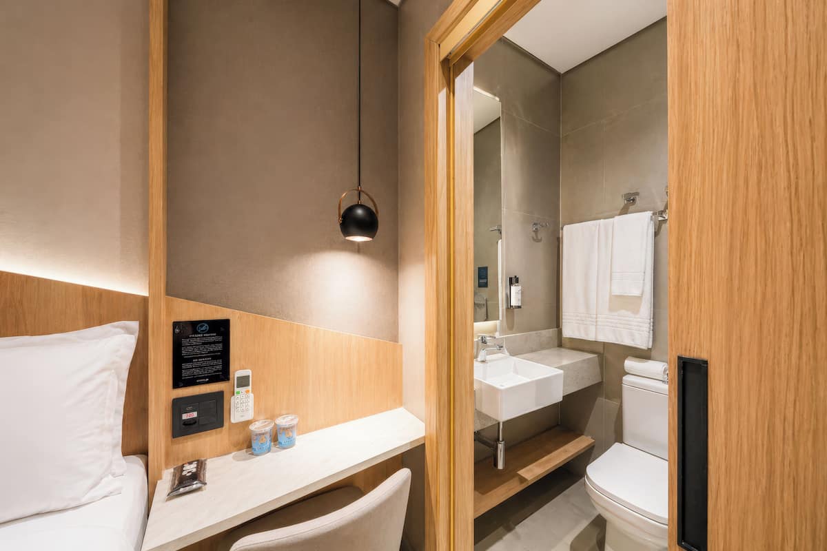 A hotel bathroom with a wooden vanity, a sink, a toilet, and a mirror.
