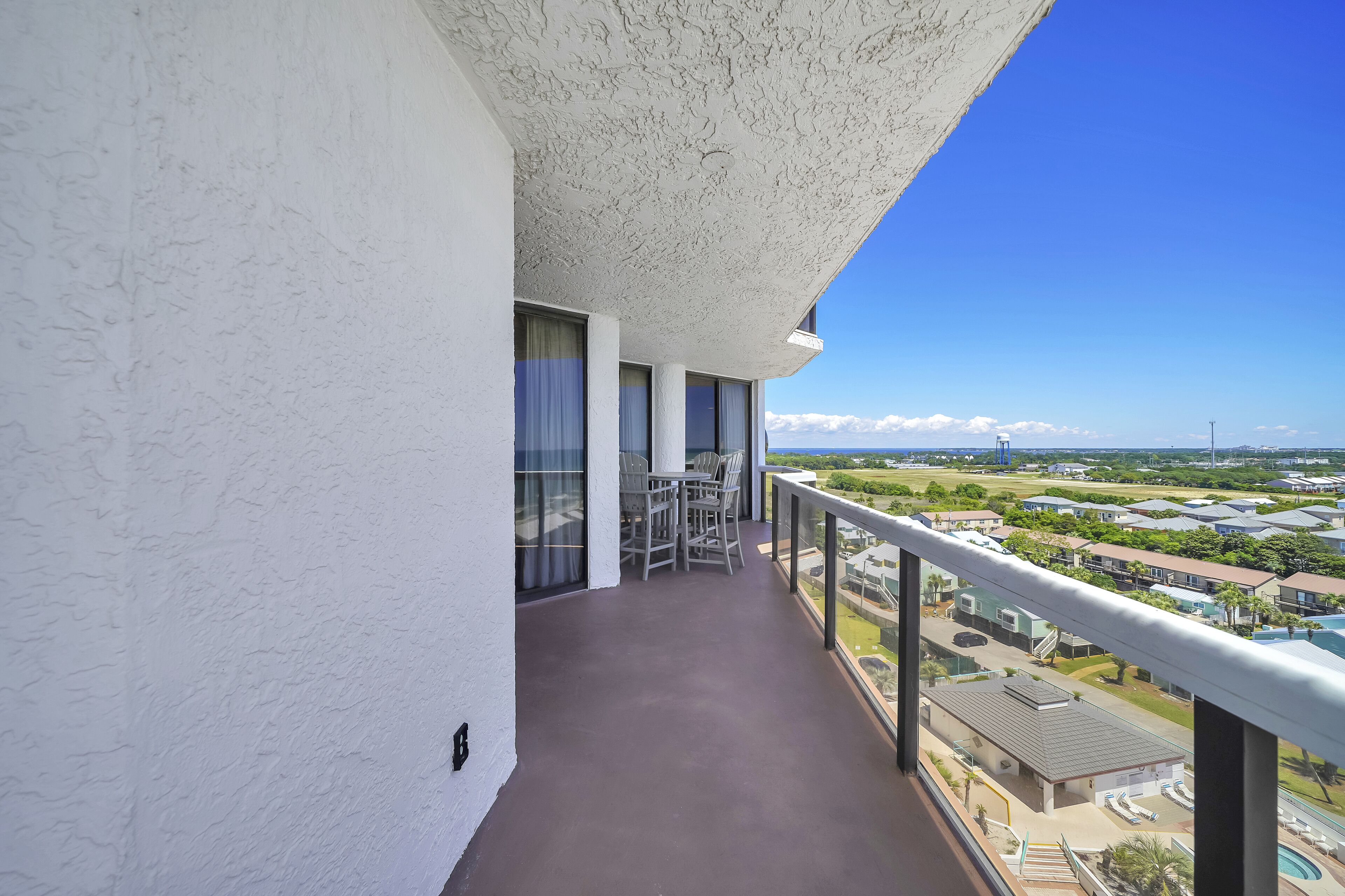 A balcony with a view of a residential area, including houses and a swimming pool.