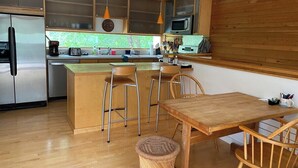 A modern kitchen with wooden cabinets, stainless steel appliances, and a central island with bar stools.
