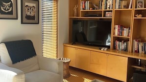A living room with a sofa, a TV, a bookshelf, and two framed owl pictures.