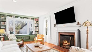Una sala de estar con chimenea, estanterías, un televisor y un tapete estampado.