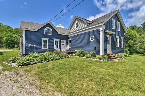A two-story house with a front porch, a garage, and a well-maintained lawn. - The Maine Retreat! Pet Friendly! (Milbridge)