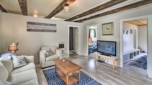 Un ampio soggiorno con divano, tavolino, televisore e soffitto a vista con travi.