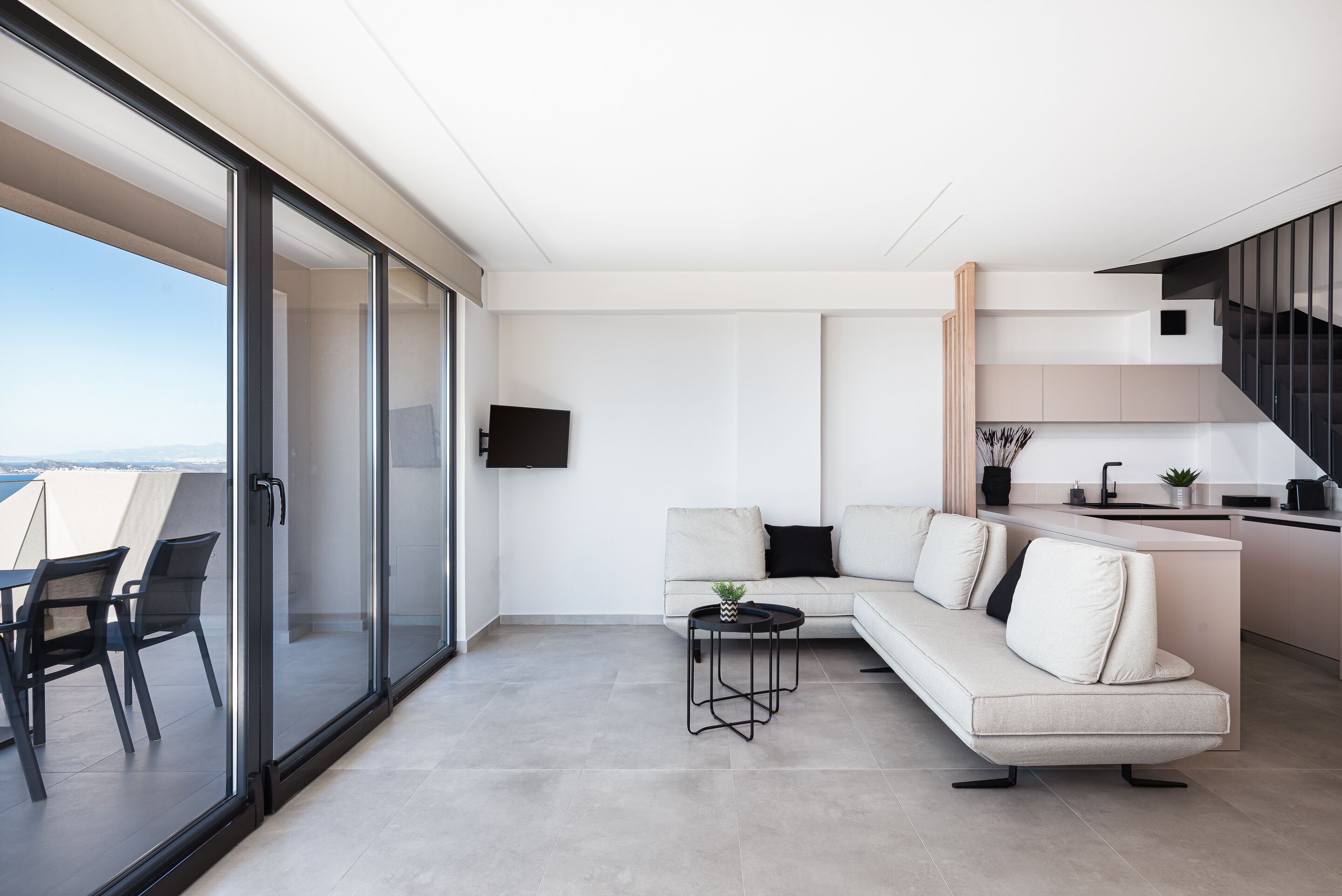 Un espace de vie moderne comprenant un canapé, une petite table et un téléviseur fixé au mur.
