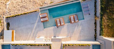A rooftop pool with lounge chairs and a view of a rocky hillside.