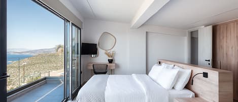 A modern bedroom with a large bed, a desk, and a view of the outdoors.
