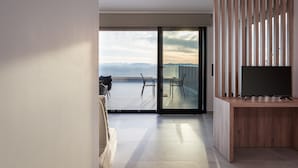 Una sala de estar moderna con un televisor grande, un escritorio de madera y un balcón con vistas a las montañas.