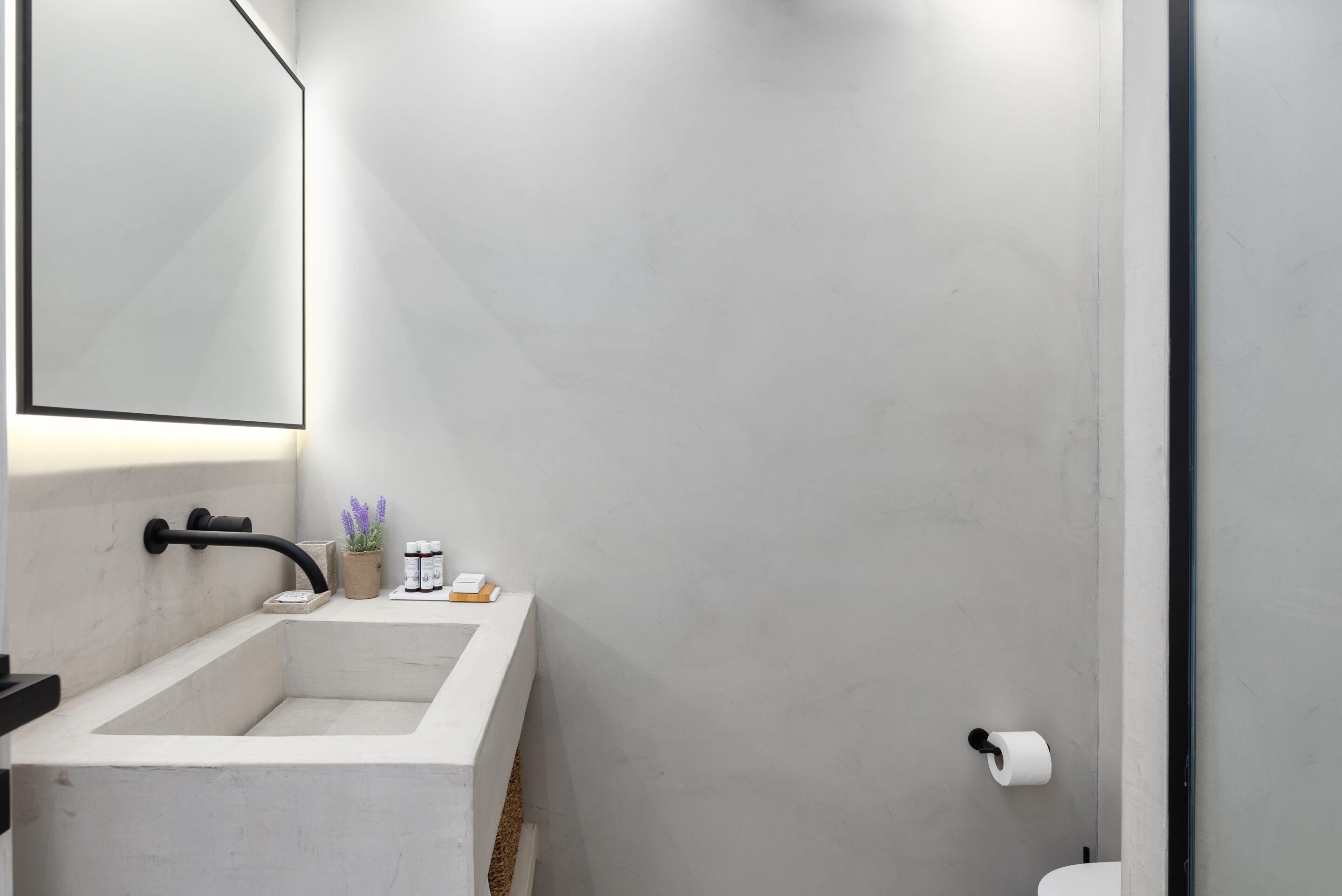 A modern bathroom with a white sink, a mirror, and a toilet.