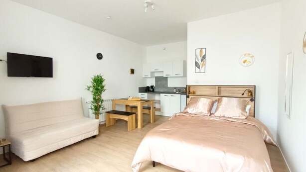 Ein gemütliches Schlafzimmer mit Bett, einer Couch, einem kleinen Tisch und einer Küchenzeile im Hintergrund.