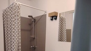 Ein Badezimmer mit Dusche, Waschbecken und Spiegel.