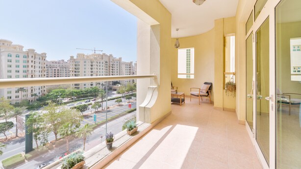 A balcony with a view of a cityscape, a small seating area with a table and chairs, and a hanging plant. - Shoreline - Luxury Palm Jumeirah (Dubai)