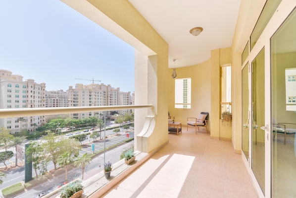 Enjoy the city view from your balcony with a seating area and potted plants.
