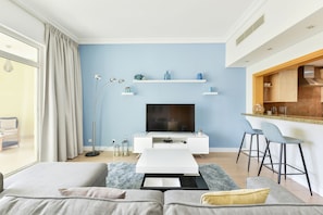 Relax in a cozy seating area with a sofa, coffee table, and flat-screen TV, or cook in the kitchen with bar stools and open shelving.