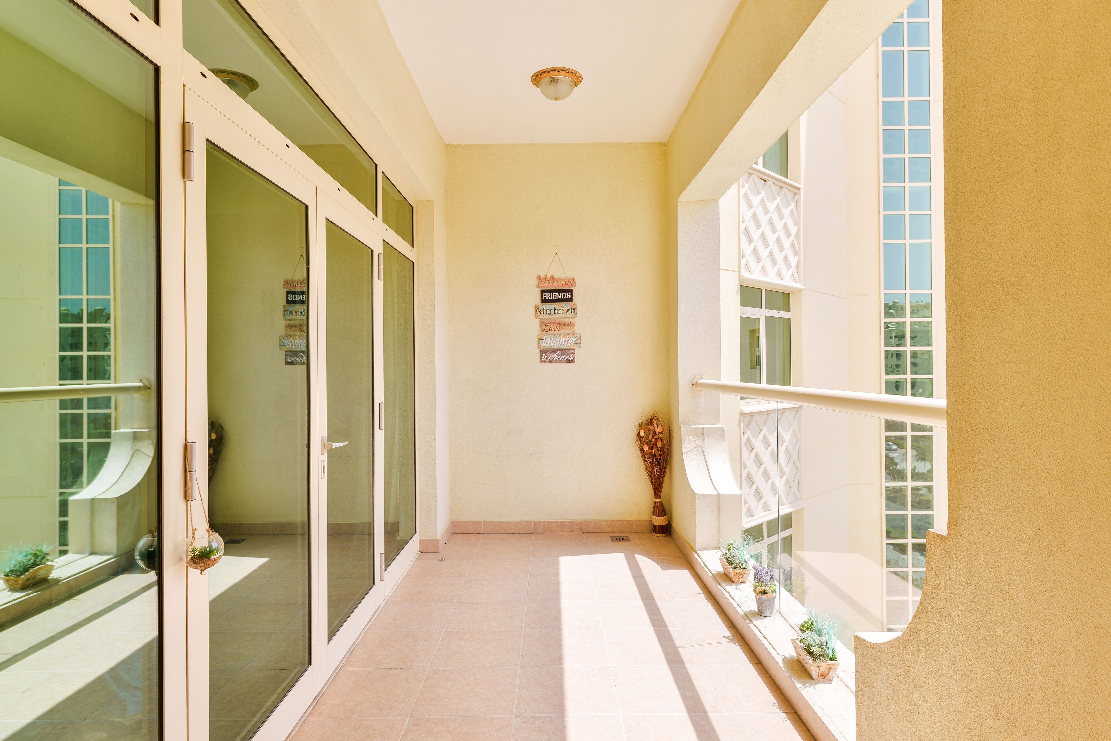 A narrow corridor with glass doors, a wall-mounted sign, and potted plants.