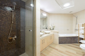 A modern bathroom with a glass-enclosed shower, a freestanding bathtub, and a vanity with a sink and mirror.