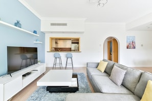Relax in this stylish living room with a flat-screen TV, comfortable sofa, and modern kitchen area.