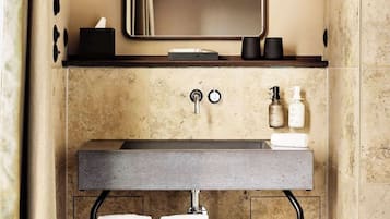 A bathroom with a large mirror, a sink with two faucets, and two towels hanging on a rack.