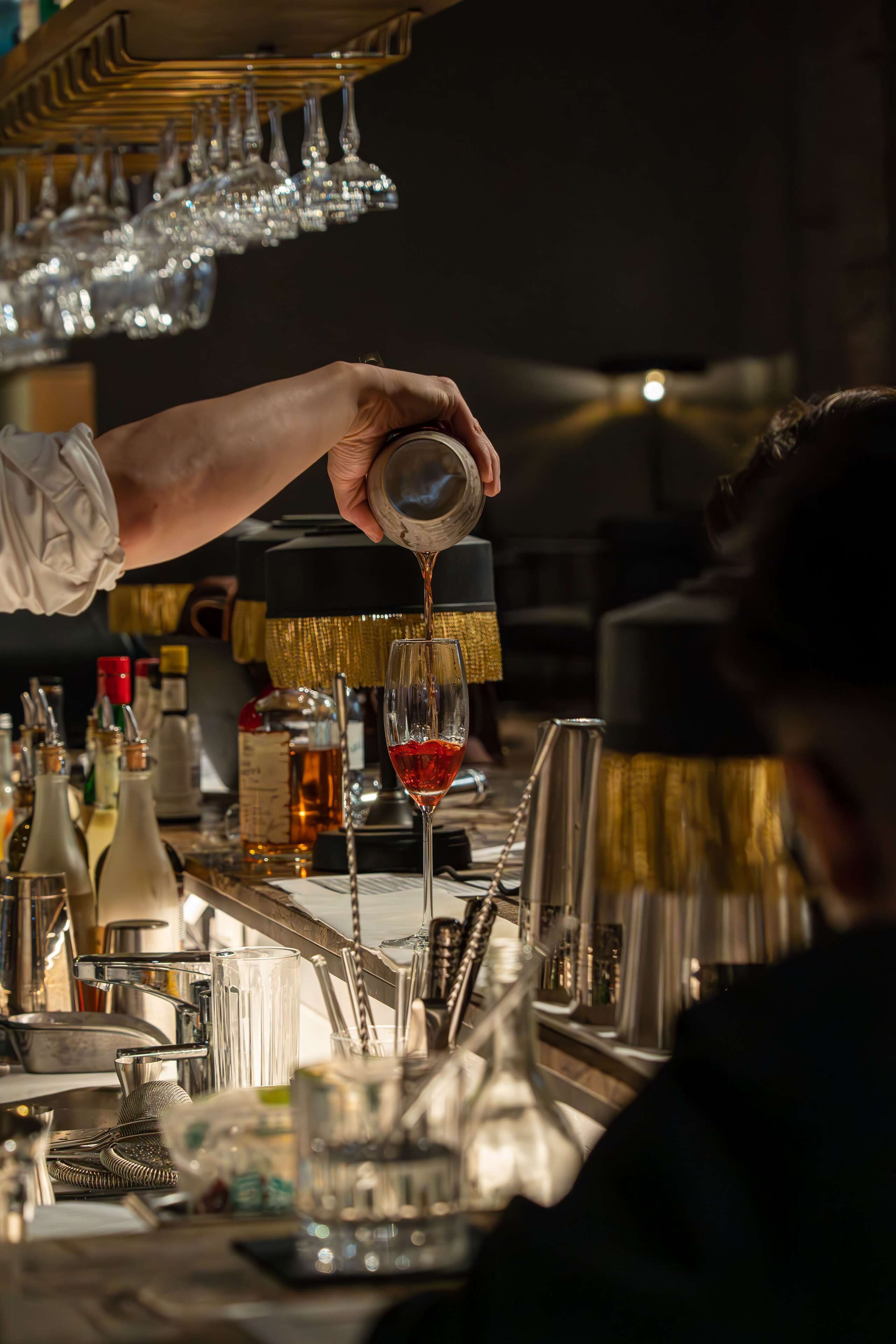 A bartender pouring a drink into a glass.
