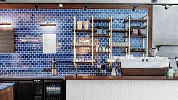 A modern bar with a blue-tiled backsplash, wooden shelves, and a white countertop.