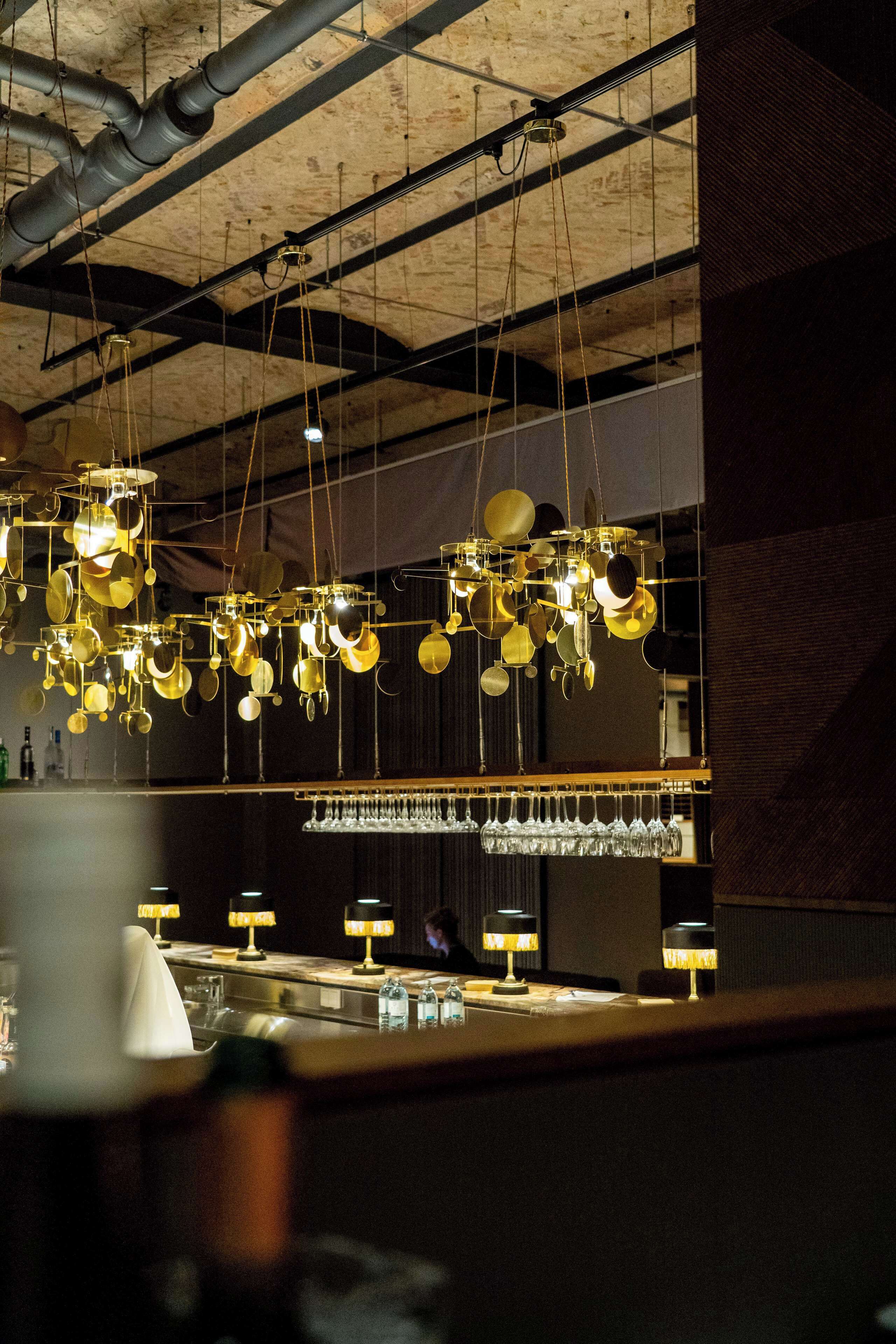 A bar area with hanging light fixtures and a wine rack.