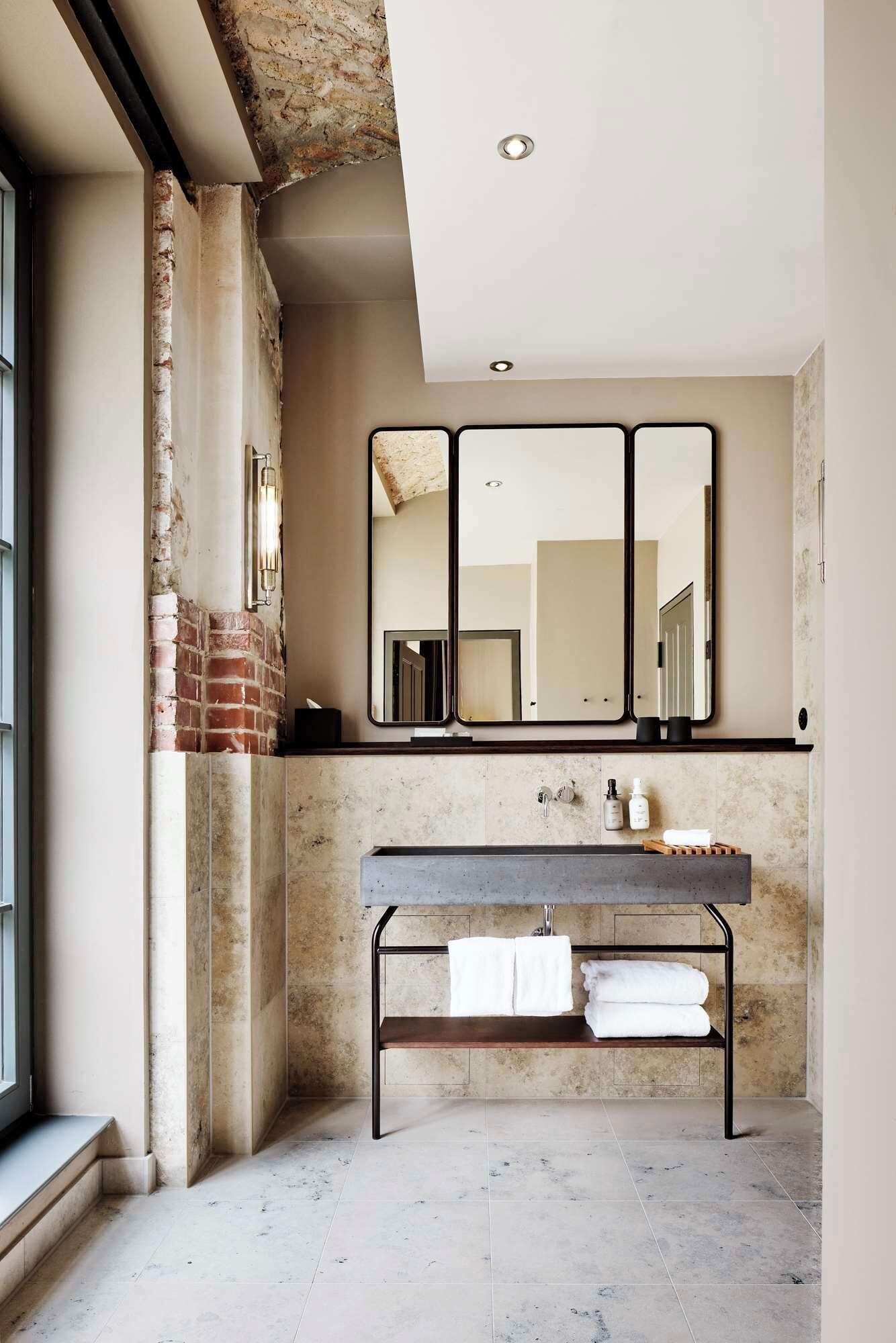 A modern bathroom with a large mirror, a sink, and a towel rack.