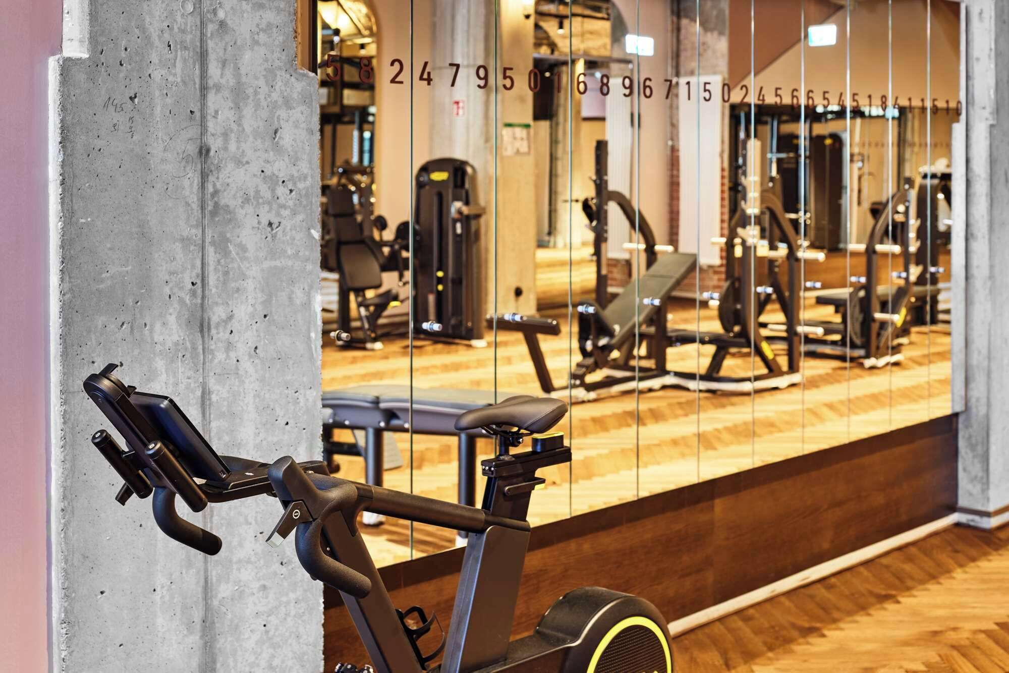 An indoor gym with exercise equipment, a mirrored wall, and a wooden floor.